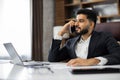 Portrait of man sitting at desk in chair having phone call with business partners in new modern office. Royalty Free Stock Photo