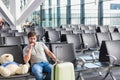 Portrait of man sitting with teddy bear and suit case while waiting for boarding in airport Royalty Free Stock Photo