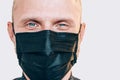 Portrait of man smiling through a black facial mask during a COVID-19 world pandemic looking at camera. Self-protection and stop Royalty Free Stock Photo