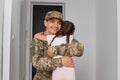 Portrait of man soldier wearing camouflage uniform and cap, posing with his kid, daughter posing backwards and hugging his lovely Royalty Free Stock Photo