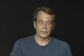 Portrait of a man in a Studio 40-50 years old in a blue t-shirt on a black blurry background, close-up. Maybe he`s just a buyer, a