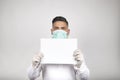 Portrait of man in surgical mask holding a white sign on white background