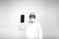 Portrait of man in surgical mask wearing white protective suit with mobile phone isolated in studio on white background. Royalty Free Stock Photo