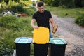 Portrait man throwing empty plastic water bottle in recycling bin. Tree recycling bins outdoors. Front view Royalty Free Stock Photo