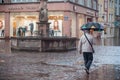 Portrait of man with umbrella on cobbles place with fountain in the city