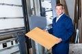 Portrait of man in uniform working on large automatic saw machinery indoors