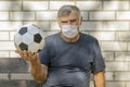 Portrait of a man using a medical health mask holding a soccer ball in his hand. Health care and healthy sport concept Royalty Free Stock Photo
