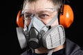 Portrait of a man wearing a respirator and protective noise-cancelling headphones earmuffs Royalty Free Stock Photo