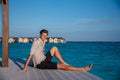Portrait of man wearing shirt sitting near water villas at the tropical beach at island luxury resort Royalty Free Stock Photo