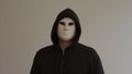 Portrait of a man wearing a white mask and black hooded hooded robe on a white background. Royalty Free Stock Photo