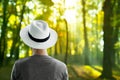 Portrait of man with white hat from the back with summer travel green orange forest nature background