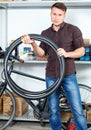 Portrait man who is standing with bicylce tires in bike store. Royalty Free Stock Photo