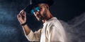 Portrait of a man in a wide-brimmed hat and sunglasses looking at camera on dark background. Royalty Free Stock Photo