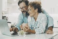 Portrait of man and woman at home enjoyng surf the web together with wireless laptop. White modern kitchen apartment in background Royalty Free Stock Photo