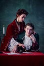 Portrait of man and woman in medieval costumes over dark green background. Writing mysterious story about vampires Royalty Free Stock Photo