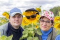 Portrait of a man and a woman with their friend sunflower in a baseball cap and glasses against the sky Royalty Free Stock Photo