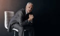 Portrait, manager or corporate with a business man sitting on a chair in studio against a dark background. Leadership