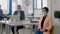 Portrait of manager with face mask sitting on chair at desk table