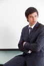 Man in dark suit and tie sitting cross-armed on desk and looking at whiteboard, copy space Royalty Free Stock Photo