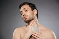 Portrait of masculine sexual man putting perfume aftershave on h