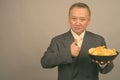 Portrait of mature Asian businessman with bowl of potato chips