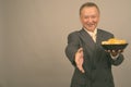 Portrait of mature Asian businessman with bowl of potato chips