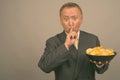 Portrait of mature Asian businessman with bowl of potato chips