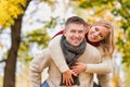 Portrait of mature attractive man giving his wife a piggy ride back in park Royalty Free Stock Photo