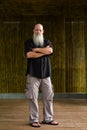 Portrait of man bald man with long gray beard standing outdoors against bamboo wall full body shot Royalty Free Stock Photo