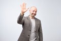 Portrait of a mature bald man in suit wave hand welcome. Human emotion expression and lifestyle concept.