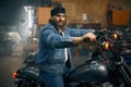 Portrait of mature bearded biker on motorcycle over garage interior