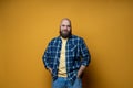 Portrait of a mature bearded man wearing plaid shirt on yellow background. Happy man looking at camera isolated over yellow