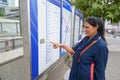 Mature beautiful Indian woman looking at train map outdoors
