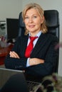 Portrait of mature boss woman in red tie at office