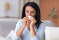 Sick mature woman sneezing and crying, holding tissue paper Royalty Free Stock Photo