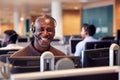 Portrait Of Mature Businessman Wearing Telephone Headset Working In Customer Services Department Royalty Free Stock Photo