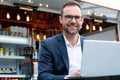 Portrait Of Mature Businessman Working On Laptop By Outdoor Coffee Shop Royalty Free Stock Photo