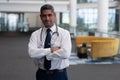 Caucasian male doctor with arms crossed looking at camera in clinic