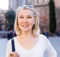 Portrait of mature cheerful woman in white blouse standing on a old city street Royalty Free Stock Photo