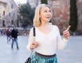 Portrait of mature cheerful woman in white blouse standing on a old city street Royalty Free Stock Photo