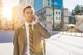 Portrait of mature confident businessman smiling and talking on smartphone while walking on pavement