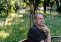 Portrait of a mature courageous man 60 years old, in a black T-shirt, sitting on a bench Royalty Free Stock Photo