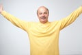 Portrait of mature european man stretching his hands wide aside looking at camera and smiling. Royalty Free Stock Photo