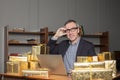 Portrait of mature excited businessman in glasses and blue suit sitting by the table with laptop and a lot of gifts around Royalty Free Stock Photo