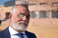 Portrait Of Mature, Executive, Gray-haired, Bearded Man In Jacket And Tie, Holding Cryptocurrency With Eye. Executive Concept,