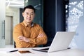 Portrait of mature experienced Asian businessman inside office at workplace, boss programmer sitting at desk with arms Royalty Free Stock Photo