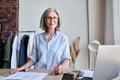 Portrait of mature fashion designer in showroom looking smiling in camera.