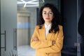 Portrait of mature female boss inside office building, successful hispanic woman in glasses and yellow jacket looking Royalty Free Stock Photo