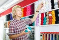 Portrait of mature female customer standing next to shelf with knitting yarn in shop Royalty Free Stock Photo