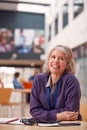 Portrait Of Mature Female Teacher Or Student With Digital Tablet Working At Table In College Hall Royalty Free Stock Photo